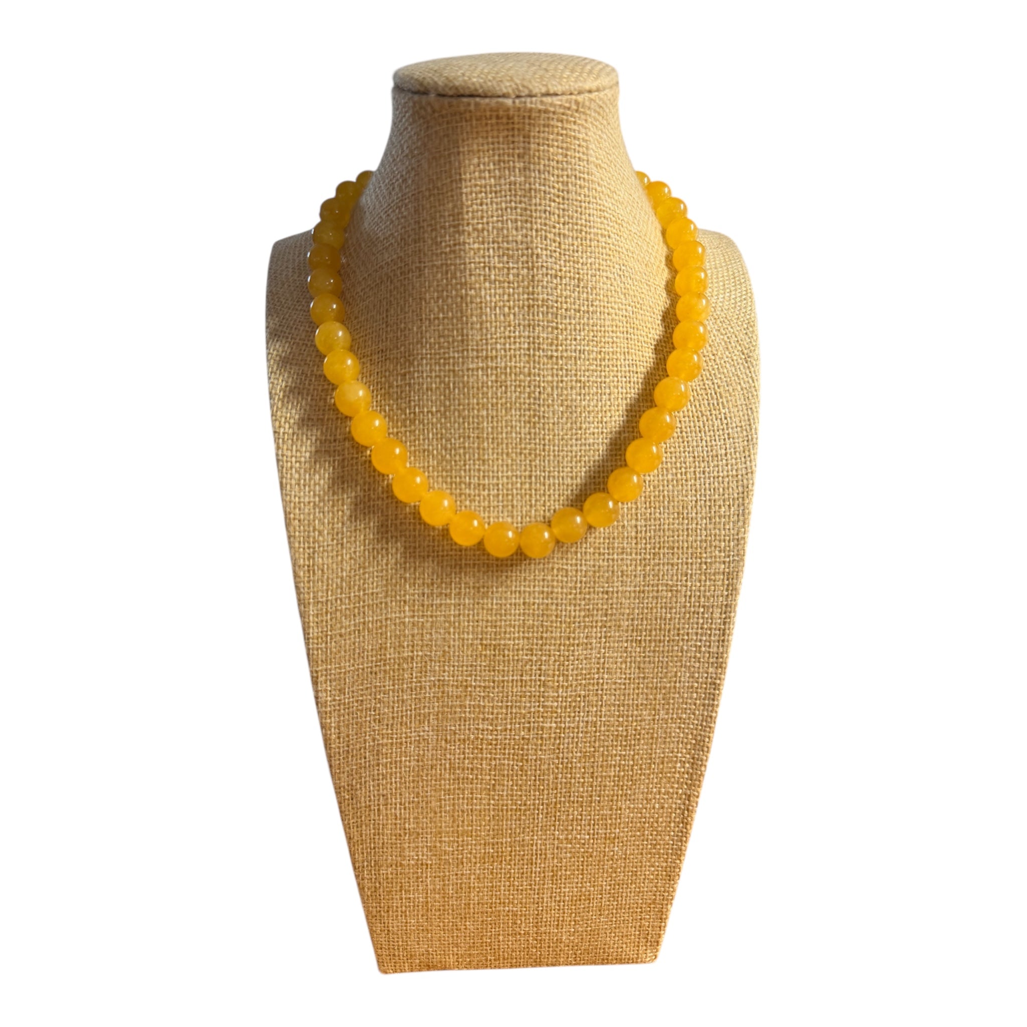 Yellow beaded necklace on a beige mannequin bust against a white background