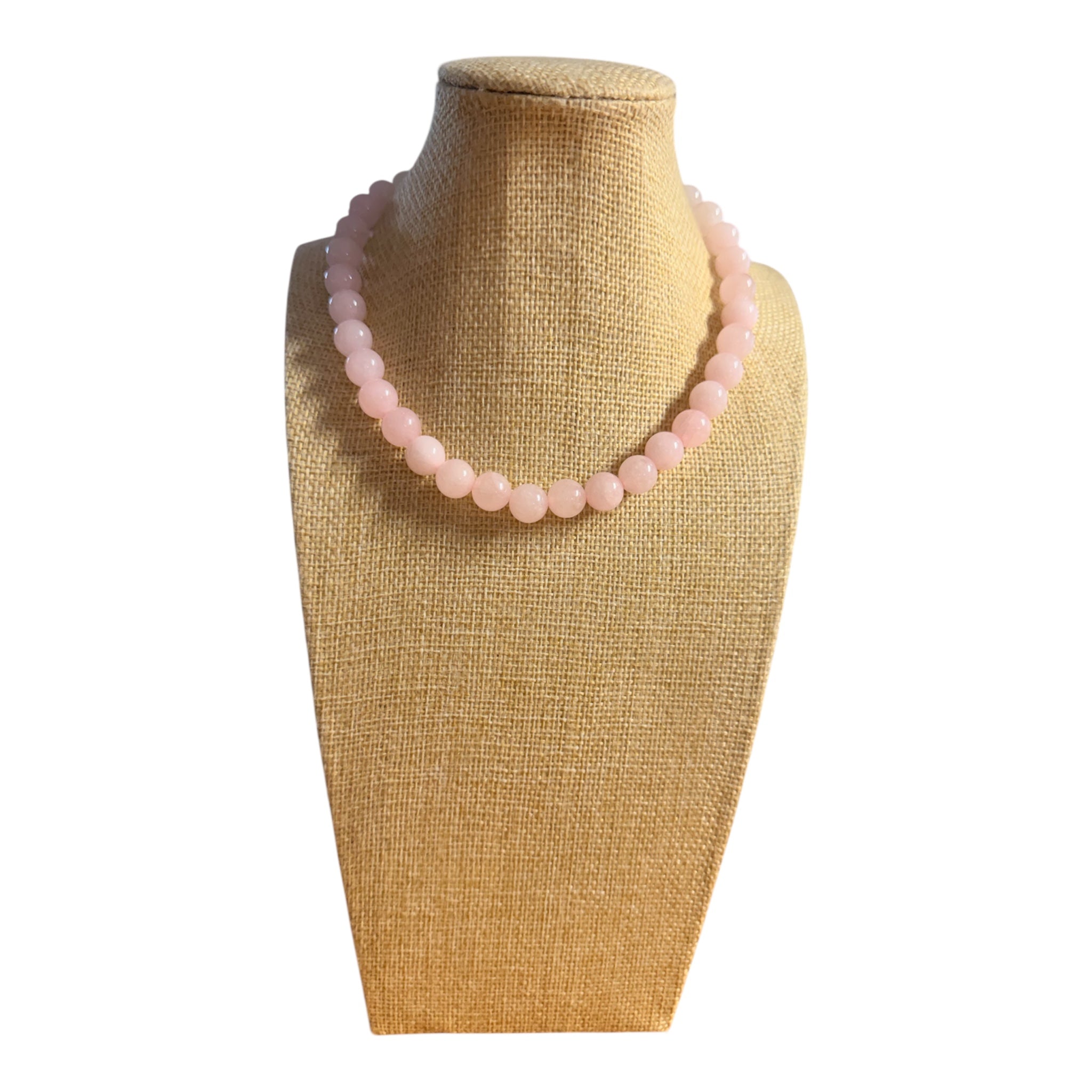 Pink beaded necklace on a gold mannequin bust against a white background