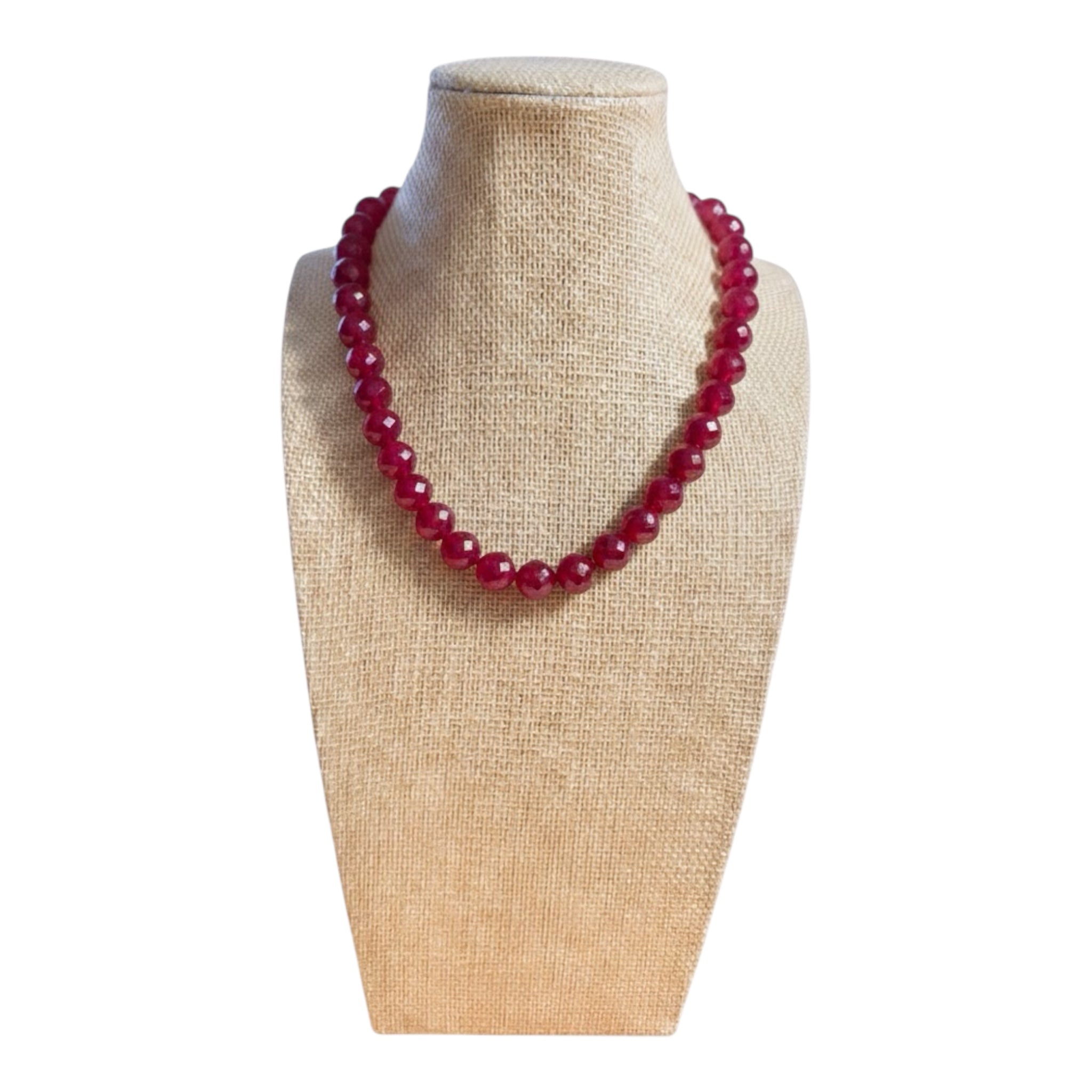Red beaded necklace on a beige mannequin bust against a white background