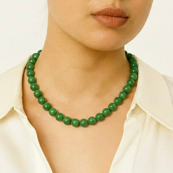 Person wearing a green beaded necklace against a plain background