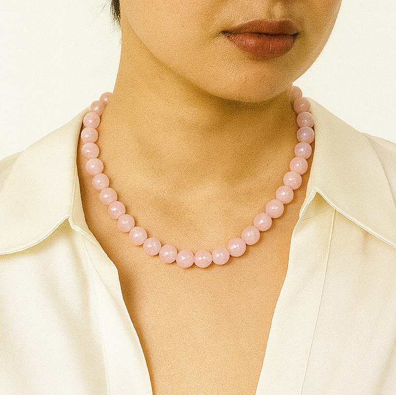 Person wearing a pink beaded necklace with a plain background