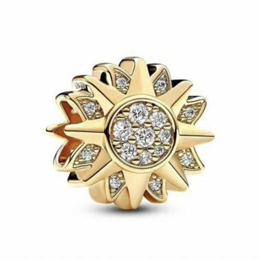 Gold sun-shaped jewelry charm with embedded diamonds on a white background