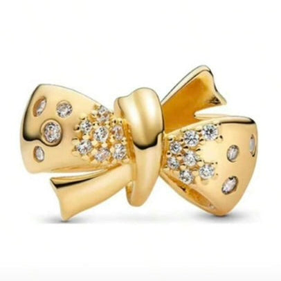 Gold bow-shaped jewelry with embedded stones on a white background