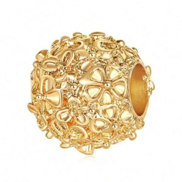 Gold charm bead with intricate design on a white background
